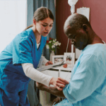 A nurse checks on an elderly male patient seated on a hospital bed during routine rounds.