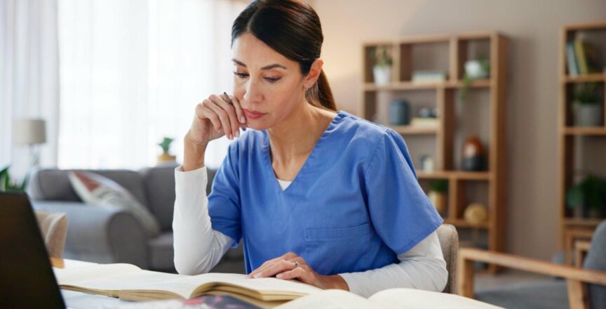 Nurse using textbook and laptop to plan care based on medical research and evidence.